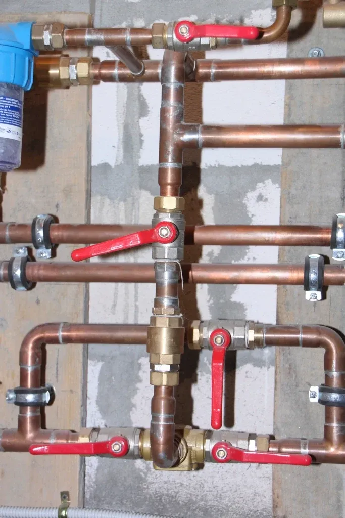A copper water valve and pipes on a wall
