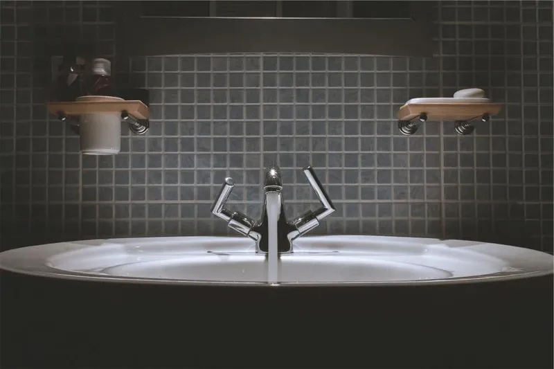 A modern bathroom basin against dark tiles